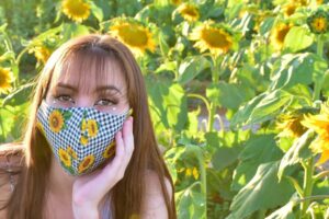 Teen in sunflower field with a mask on