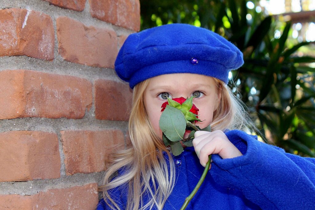 girl in blue hat and coat with rose