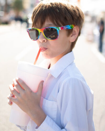 boy with rainbow sunglasses drinking a soda