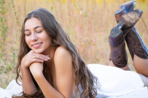 senior grad girl in white dress and cow boy boots in Gilbert AZ. Beautiful photo.