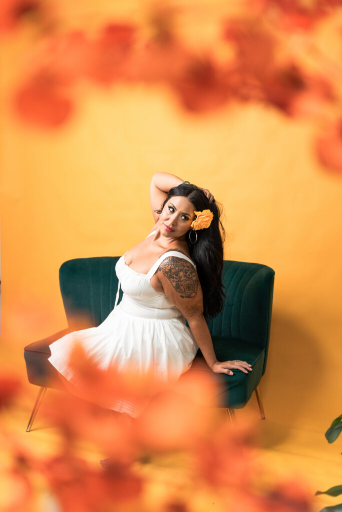 TC posing among tropical plants and flowers in front of a bright yellow backdrop during a Tropical Sunshine studio photoshoot.
