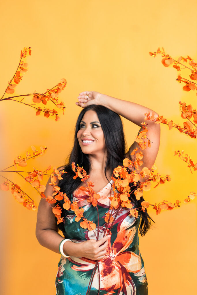 TC smiling while posing with tropical plants and flowers during a creative studio photoshoot in Peoria, Arizona.