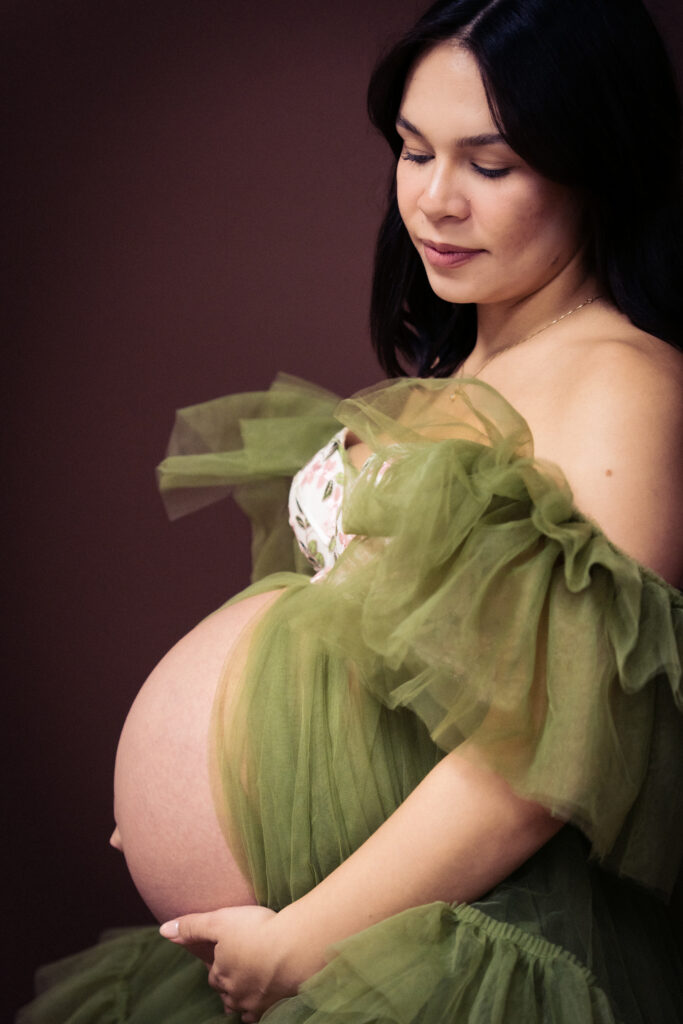 Studio portrait of photographer Vyna wearing a olive green gown against a brown backdrop at Vision Studio in the Phoenix West Valley.